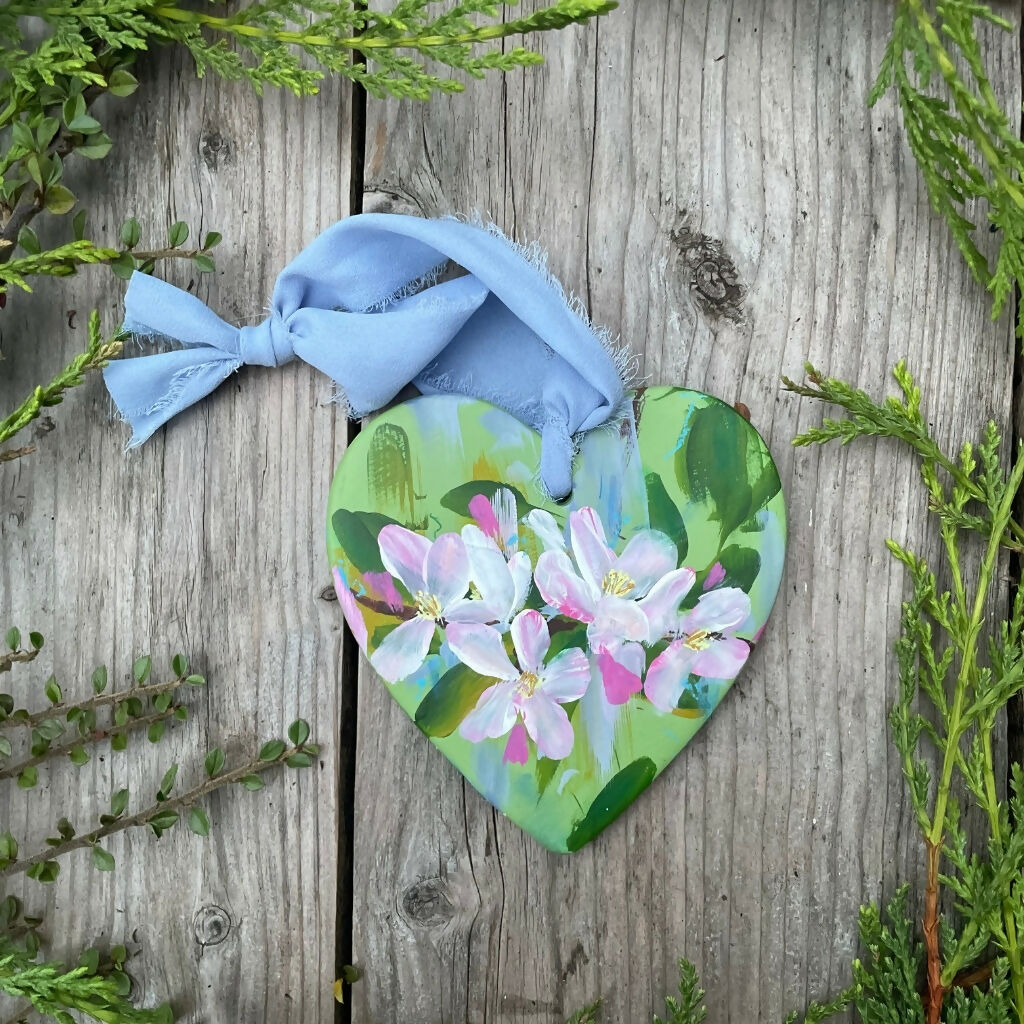 hand painted floral ceramic hanging heart green background with apple blossom flowers.