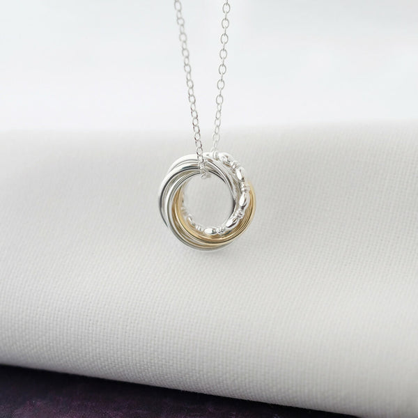 A 9ct gold and sterling silver 60th birthday necklace hanging over white material.