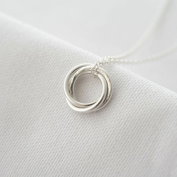 A close up of a sterling silver 30th birthday necklace displayed over white material.