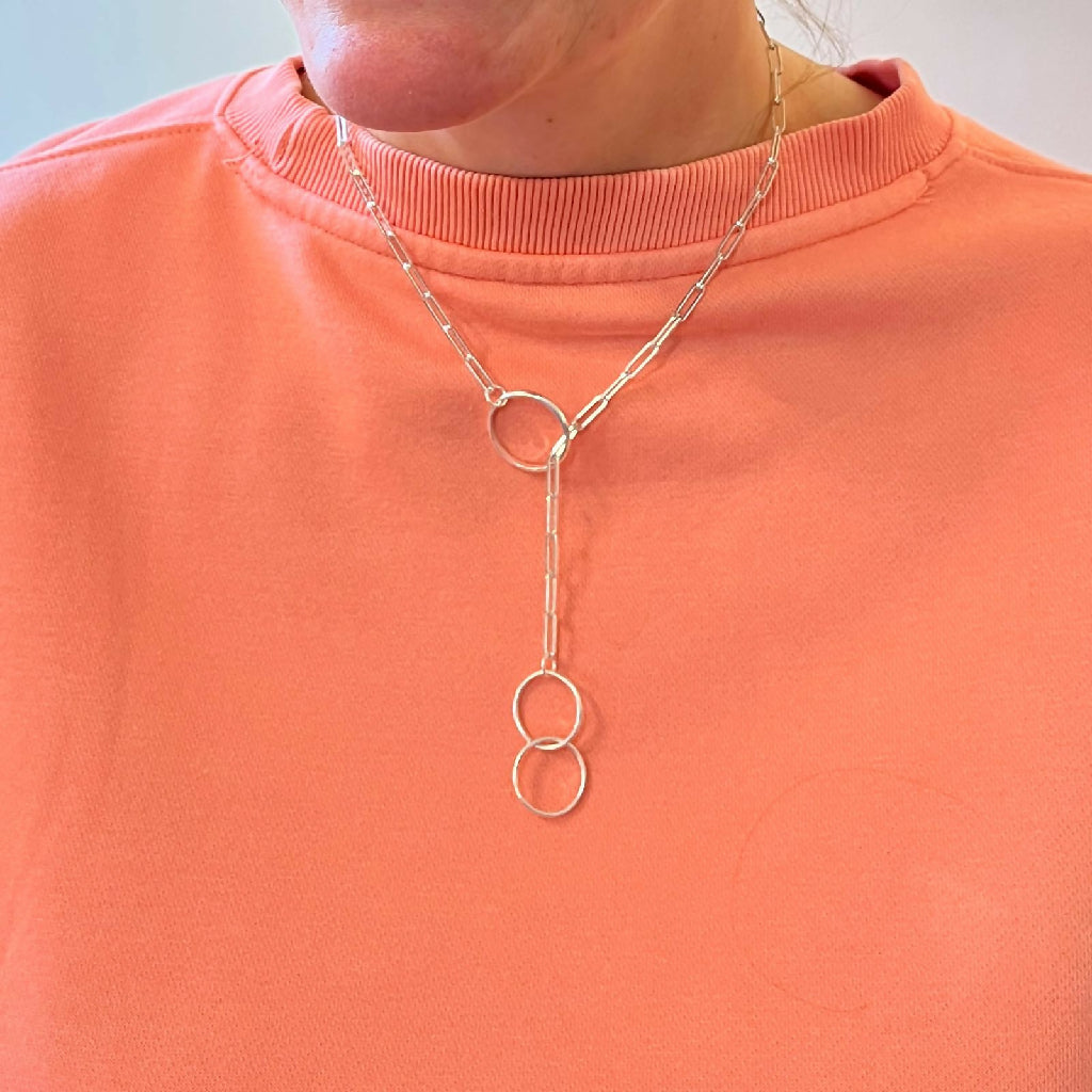 Handmade sterling silver lariat necklace with 3 hoops shown being worn by a model