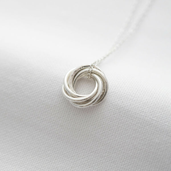 A sterling silver 60th birthday necklace displayed over white material.