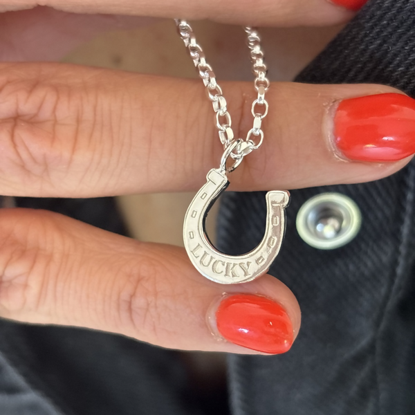 Silver horse should with the word lucky engraved on the bottomHeld by a human hand