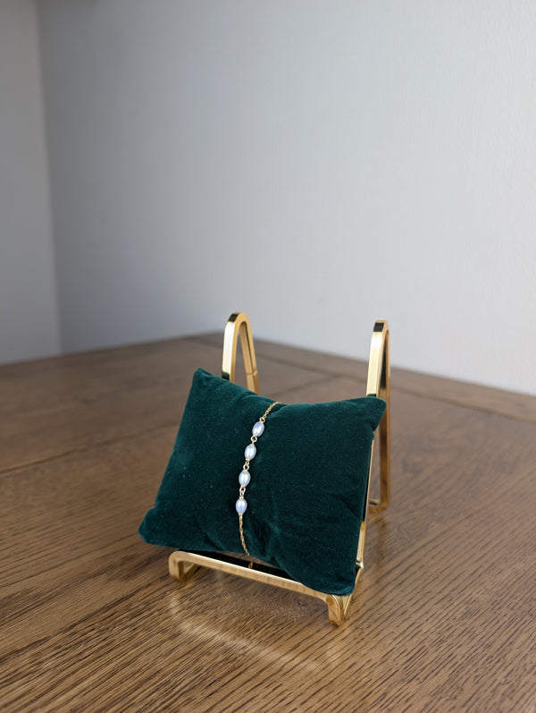 Green velvet jewelry display with a gold stand on a wooden surface
