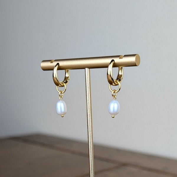 Gold earring stand with hanging earrings on a wooden surface