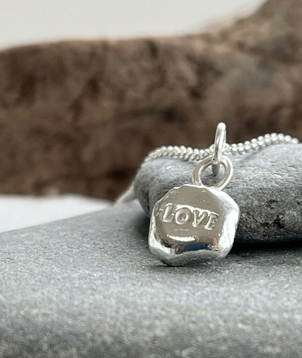 A recycled silver ‘LOVE’ stamped pebble pendant necklace