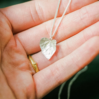 silver ivy leaf necklace held in hand