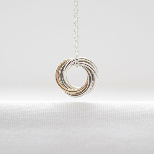 A gold and silver 50th birthday necklace hanging over white material.