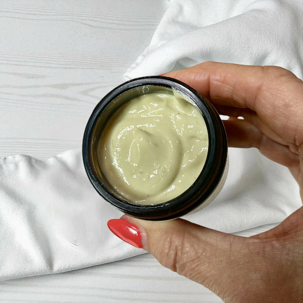 sleep magnesium cream with hand holding jar with lid off to show consistency made by buddha and bubbles botanicals uk