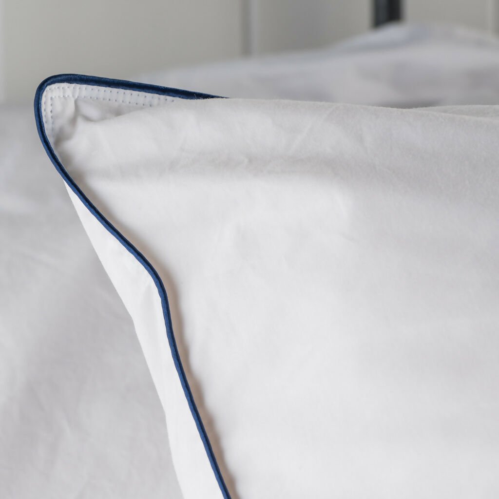 white pillowcover with navy bluw pipe edged