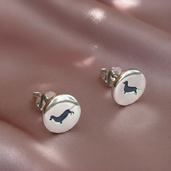 Round silver stud with sausage dogs engraved on the front in blue