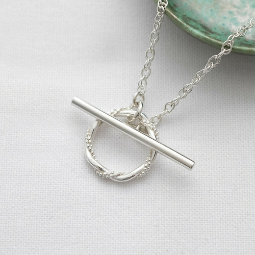 A sterling silver toggle clasp necklace displayed on white material.