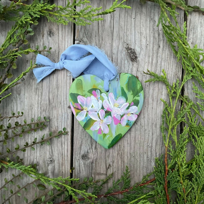 hand painted floral ceramic hanging heart green background with apple blossom flowers.