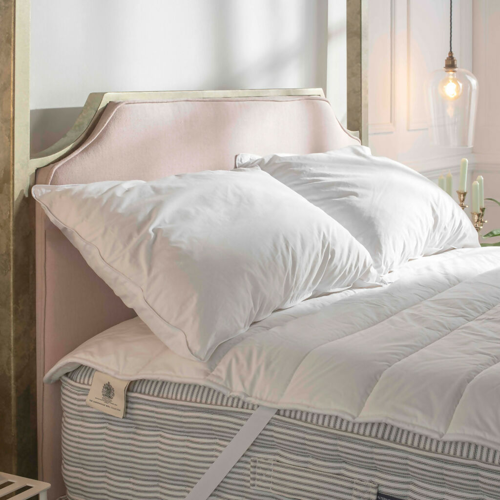 Pair of organic traceable british wool pillows resting against an upholstered headboard