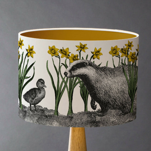 Whimsical lampshade featuring a surprised badger and charming duckling among golden yellow daffodils in a British countryside scene.