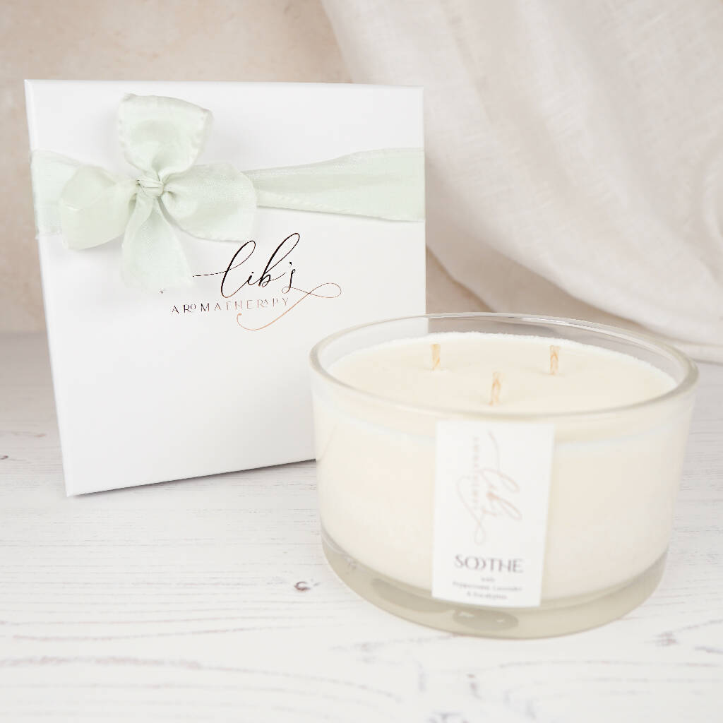 A soothing candle with 3 wicks next to its box