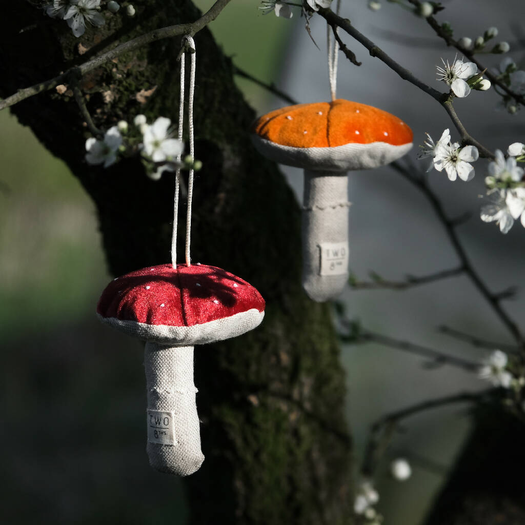 Two velvet fabric toadstools hanging from a tree.