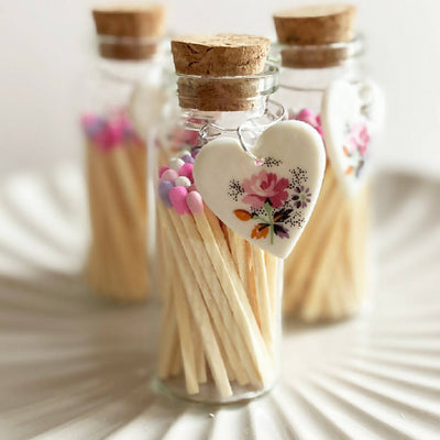A Bottle Of Rose Matches And Porcelain Heart Charm