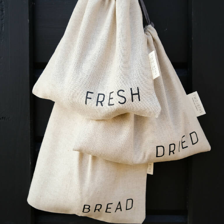 Set of three linen produce bags hanging from a hook.