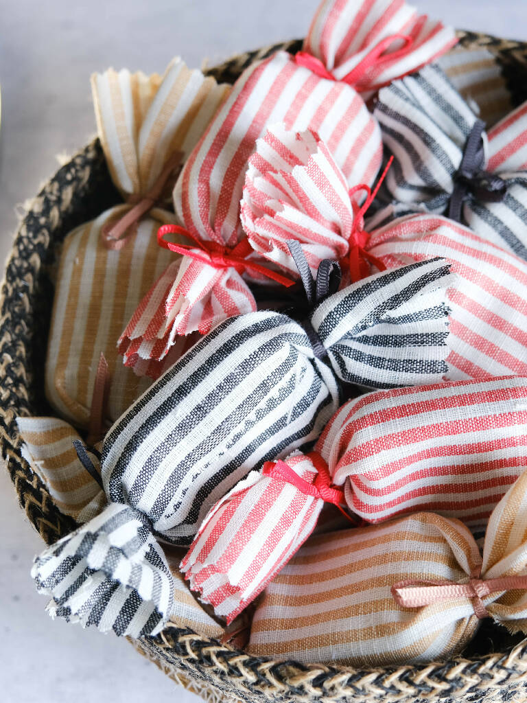 A basket full of fabric wrapped humbug wedding favours.