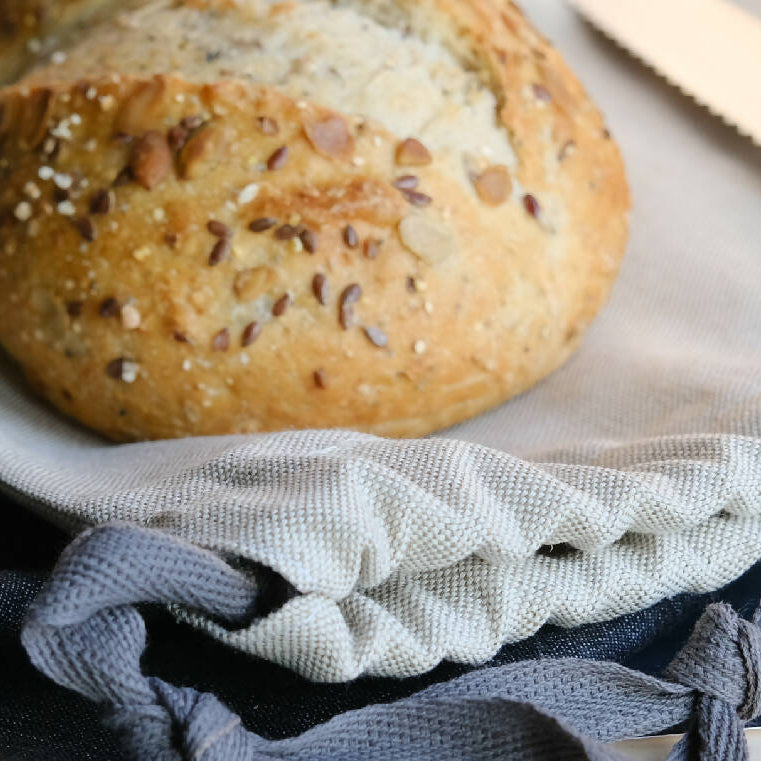 A loaf of bread sat on top of a linen drawstring bread storage bag.