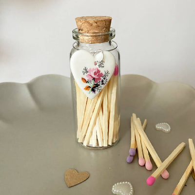 A Bottle Of Rose Matches And Porcelain Heart Charm